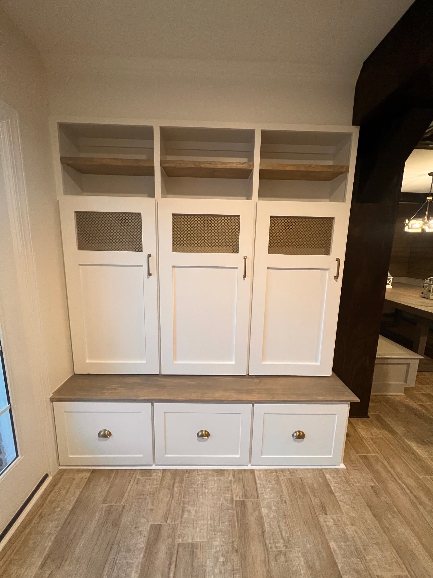 Custom white mudroom lockers with bench seating, drawers, and stained wood shelving
